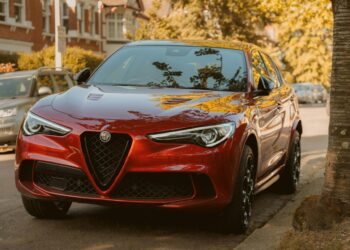 A red alfa romeo suv is parked on the street.